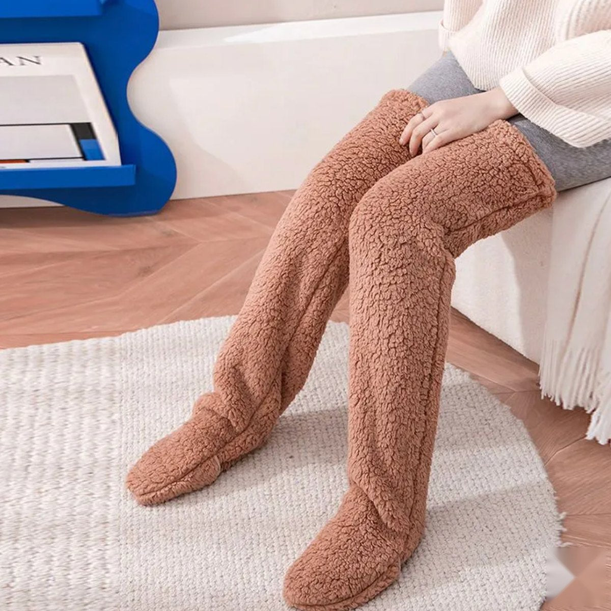 Brown Fuzzelle slipper socks worn over the knee on the couch